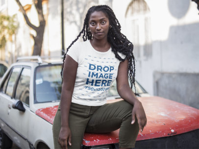 Mockup of a Woman Sitting on an Old Car While Wearing a Tee in the Street 