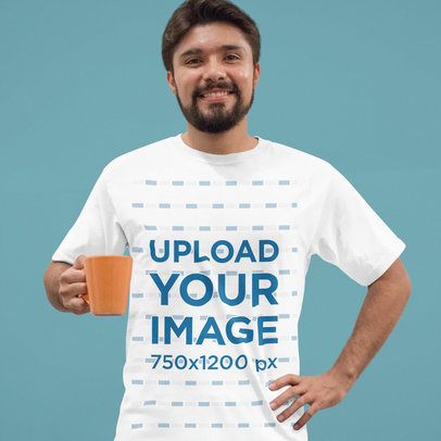Young Hispanic Guy Wearing a Round Neck Tshirt Template While Holding a Cup of Coffee Against a White Wall