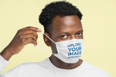 Mockup of a Man Putting a Face Mask on in a Studio