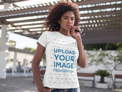 Mockup of a Woman Wearing a Round Neck T-Shirt While Holding her Glasses Outdoors