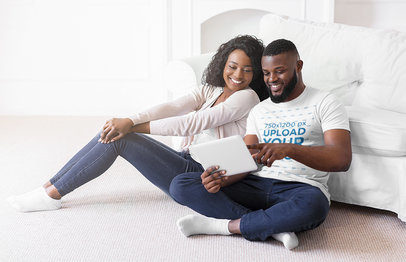 T-Shirt Mockup of a Couple Checking a Tablet in their Living Room
