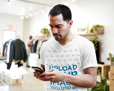 V-Neck T-Shirt Mockup of Man Checking Up His Phone in a Store