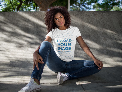 Mockup of a Woman Wearing a Round Neck T-shirt While Sitting Down Outdoors