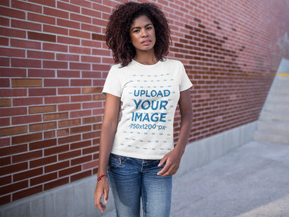 T-Shirt Mockup Being Worn by a Woman Standing Near a Bricks Wall