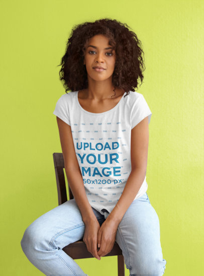T-Shirt Mockup of a Curly-Haired Woman Sitting On a Chair at a Studio 