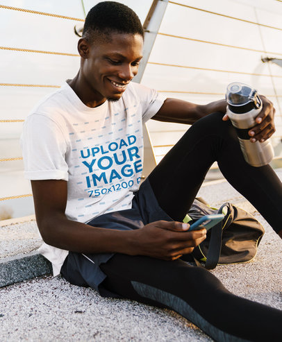 T-Shirt Mockup of a Happy Man Checking His Phone After Training