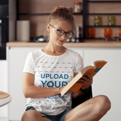 T-Shirt Mockup of a Woman Posing with a Book in Hand at Home