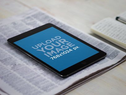 Mockup of an iPad Mini Placed over a Newspaper