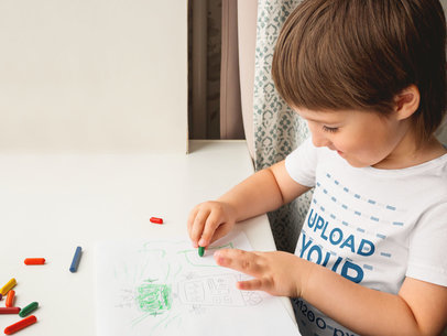 T-Shirt Mockup of a Little Boy Drawing With Crayons