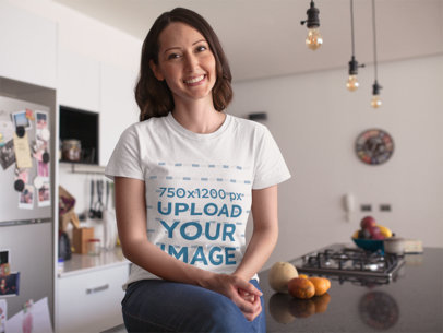 Happy Hispanic Woman Sitting Down in the Kitchen While Wearing a Round Neck Tee Mockup