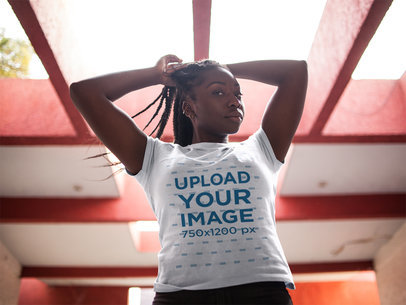 Woman Fixing her Locs While Wearing a Round Neck Tee in an Urban Structure