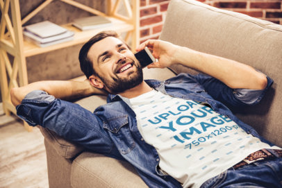 T-Shirt Mockup of a Happy Man Lying on a Couch While Talking on the Phone