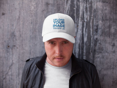Front Shot of a White Guy Wearing a Hat Mockup While Standing Against a Concrete Wall