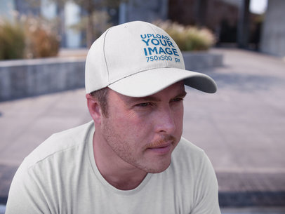 White Guy Wearing a Dad Hat Mockup While Sitting Down Outdoors