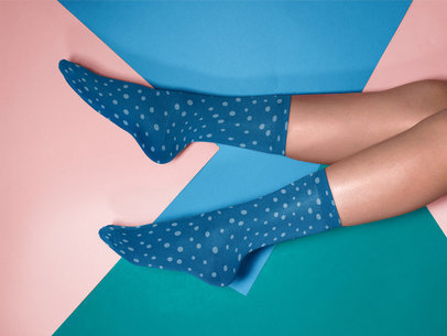Mockup of a Pair of Socks Being Worn While Lying on a Multicolor Surface a15596