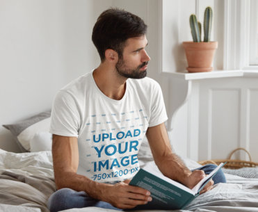 T-Shirt Mockup Featuring a Man Reading a Book on a Bed
