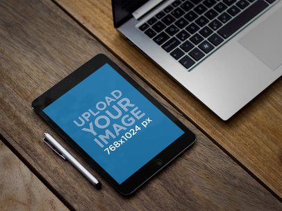 Mockup of an iPad Mini in Portrait Mode Placed Next to a Laptop