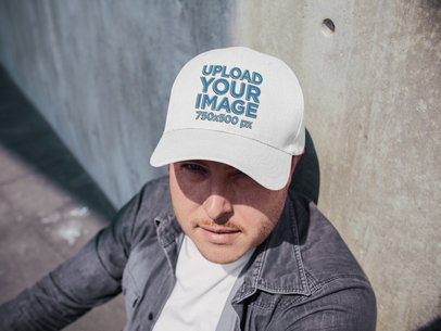 Middle Aged White Guy Wearing a Hat Mockup While Lying Against a Concrete Wall