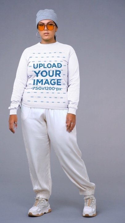 Sweatshirt Mockup Featuring a Woman Posing at a Studio With a Beanie and Sunglasses