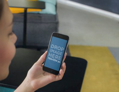 iPhone Mockup of a Woman Using a Black iPhone 6 at Colorful Lounge