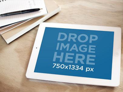 Mockup of an iPad on a Wooden Table with Notebook