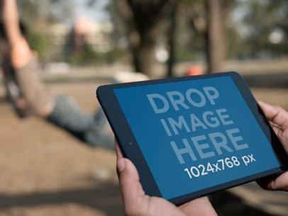 Mockup of a Man Using an iPad at a Park 