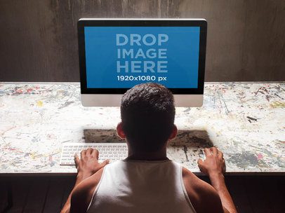 Mockup of a Young Man at a Creative Studio Using an iMac