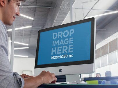 Mockup of a Young Male Intern at an Office Using an iMac