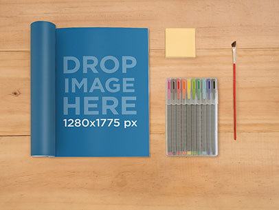 Magazine Mockup Lying on Top of a Wooden Desk at a Design Studio