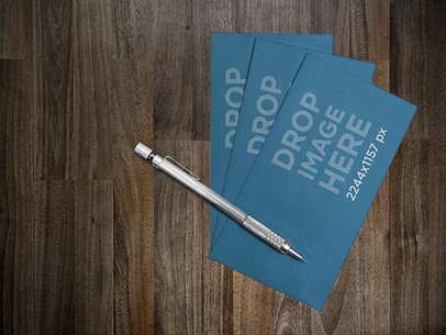 Mockup Featuring a Set of Business Cards Lying Next to a Pen on a Desk