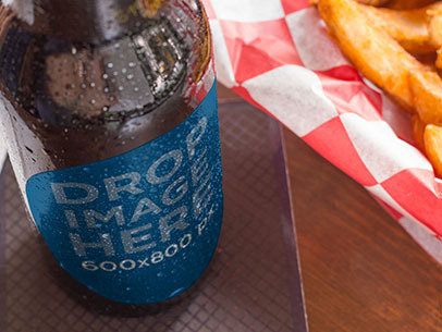 Label Mockup of a Beer Bottle Standing Next to a Plate of Fries