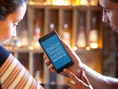 iPhone Mockup Featuring a Couple Using an iPhone 6 at a Restaurant