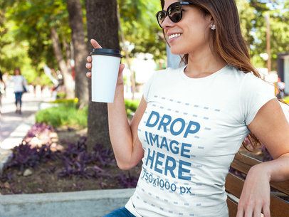 T-Shirt Mockup of a Woman Having a Coffee at a Park