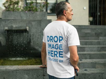 Elder Man Wearing a Round Neck Tee Mockup Standing Near a Fountain