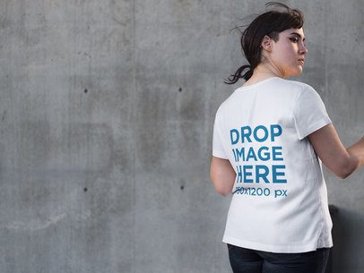 Back of an Alternative Woman Wearing a T-Shirt Mockup while Facing a Concrete Wall