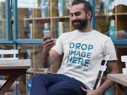 T-Shirt Mockup of a Man Using His iPhone Outdoors