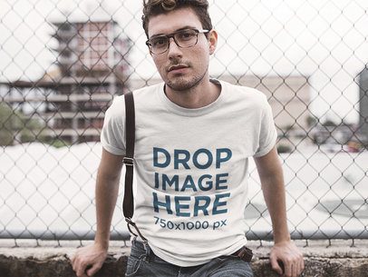 Tee Mockup of a Young Man Leaning on a Wired Fence