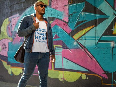 Tee Mockup of a Man Walking by a Graffiti Wall