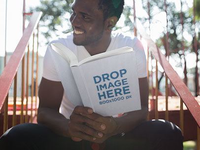 Young Man Holding a Paperback Book Mockup 