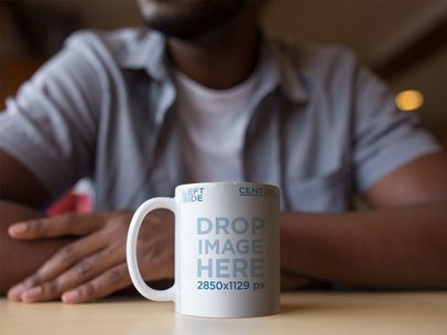 11 oz Coffee Mug Mockup Featuring a Man Sitting at a Table