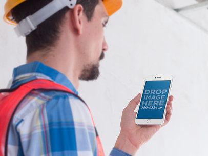 Mockup of a Construction Worker Holding an iPhone 6 in Portrait Position 
