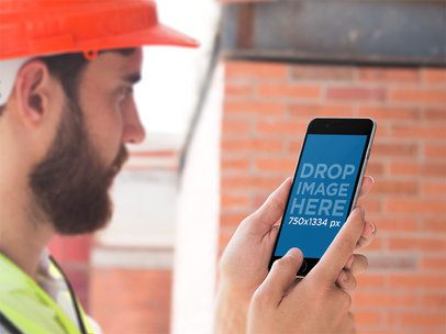 Mockup of a Man Using an iPhone in Portrait Mode Against a Brick Wall