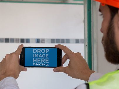 iPhone Mockup of a Construction Man Taking a Picture in Landscape Mode 12422