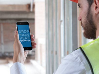 Over Shoulder Mockup of a Worker Holding His iPhone in Portrait Mode