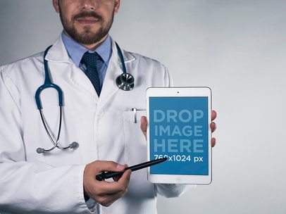 Mockup of a Bearded Doctor Pointing at His iPad in Portrait Mode