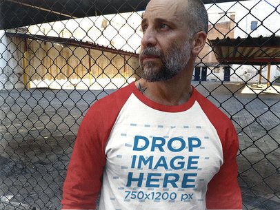 Middle-Aged White Man Staring Away and Leaning Against a Rusty Fence Raglan Tee Mockup