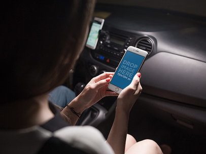 Mockup of a Woman Looking at an iPhone in Portrait Position in a Car