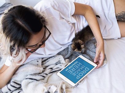 Young Woman in Bed with her Cat Using her iPad Mini Mockup a12813