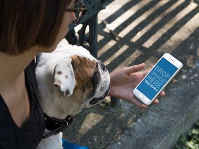 Mockup of a Woman with a Dog holding an iPhone in Portrait Position