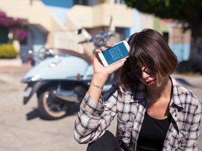 iPhone Mockup in Portrait Position Featuring a Woman with a Vintage Scooter in the Background